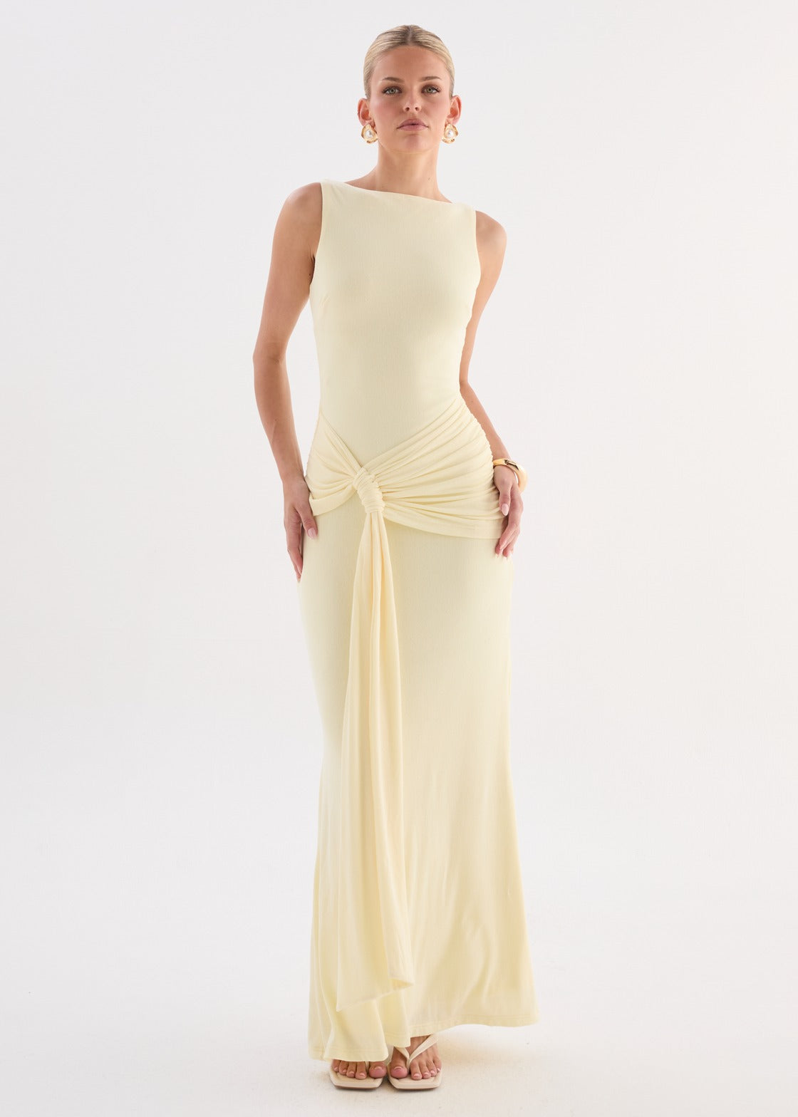 Model wearing a butter yellow sleeveless maxi dress with gathered waist and draped tie